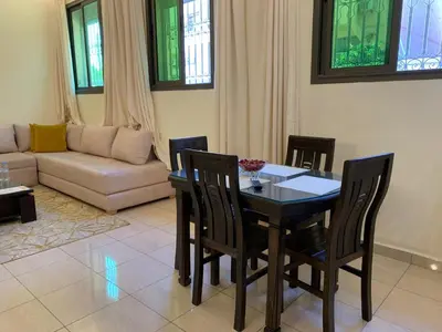 a living room with a table and chairs and a couch at Appartements du luxe in Marrakech