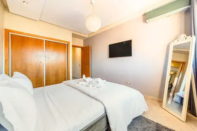 a bedroom with a white bed and a mirror at Cocon de Guéliz - Central & balcon in Marrakech