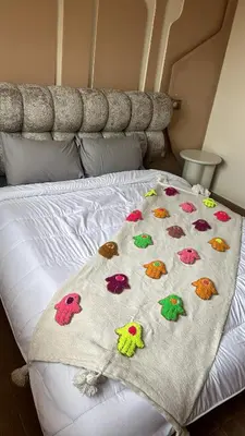 a bed with a blanket with colorful birds on it at Bel appartement neuf in Marrakech