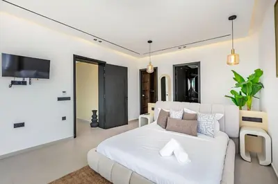 a white bedroom with a white bed and a tv at Luxury Villa, Design, Comfort, Heated Pool, Games in Marrakech