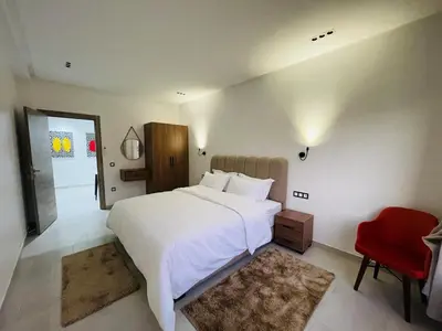 a bedroom with a large white bed and a red chair at The Pearl Loft, Marrakech Luxury Apartment in Marrakech