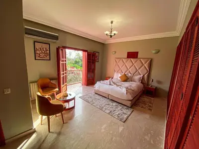 a bedroom with a bed and a table and a chair at Villa Dar Zitoune in Marrakech