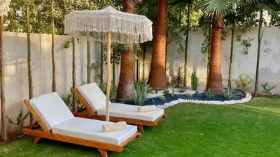 two chairs and an umbrella in a yard with palm trees at Villa de Rêve sans vis-à-vis à Marrakech in Marrakech