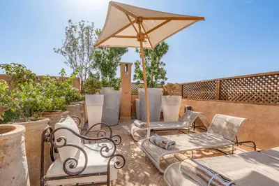 a patio with two chairs and an umbrella at Riad Royal Koubba in Marrakech