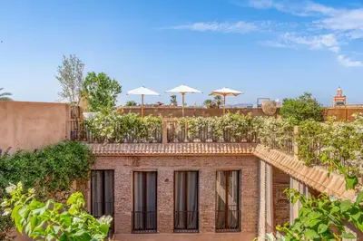 a brick building with a balcony with umbrellas at Riad Royal Koubba in Marrakech