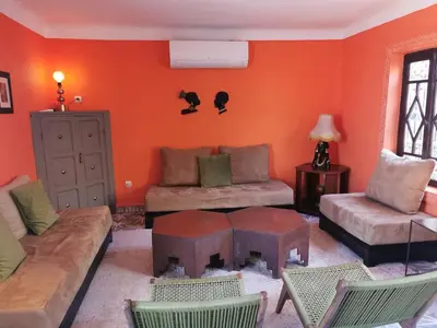 a living room with orange walls and a couch and chairs at Dar Ahlam in Marrakech