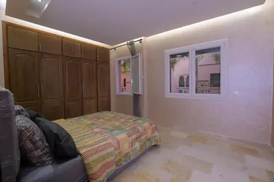 a bedroom with a bed and two windows at Appartement calme avec piscine et parking in Marrakech