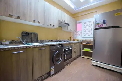 a kitchen with a refrigerator and a washer and dryer at Appartement calme avec piscine et parking in Marrakech