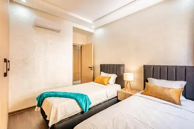 two beds in a small room with two lamps at comfortable equipped apartment in Marrakech