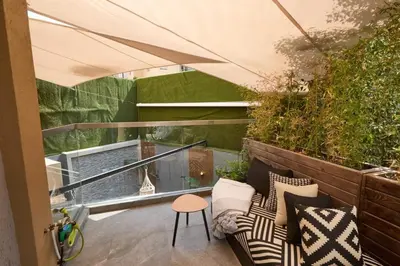 a patio with a couch and a stool on a balcony at Luxurious duplex with a private pool in Marrakech