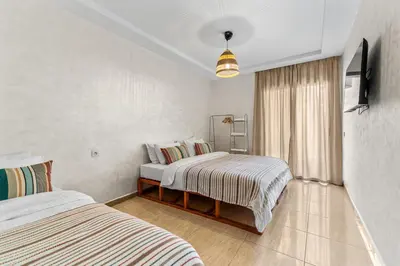 a bedroom with two beds and a television in it at Massira Social Living in Marrakech