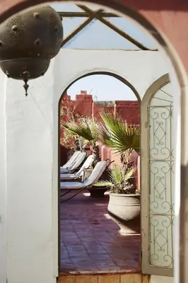 an archway leading to a patio with chairs and plants at Riad Les Jardins d'Henia in Marrakech