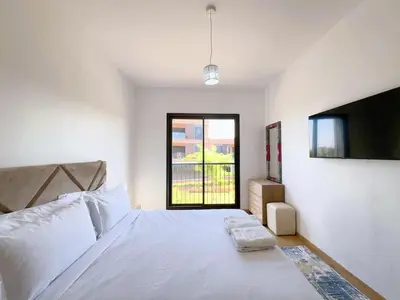 a bedroom with a large white bed with a window at Noria Golf Elegance Pool with View in Marrakech