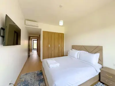 a bedroom with a white bed and a television at Noria Golf Elegance Pool with View in Marrakech