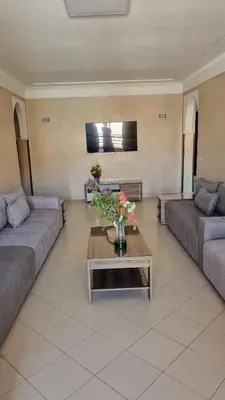 a living room with two couches and a table with flowers at Happy Relaxing home in Marrakech