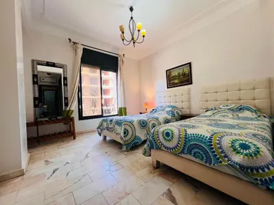 a bedroom with two beds and a chandelier at Résidence belle vie 6 avec piscine in Marrakech