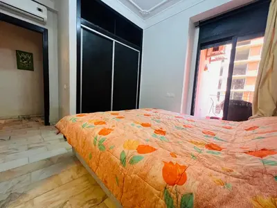 a bedroom with a bed with an orange comforter at Résidence belle vie 6 avec piscine in Marrakech