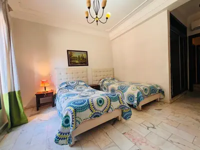 a bedroom with two beds and a chandelier at Résidence belle vie 6 avec piscine in Marrakech