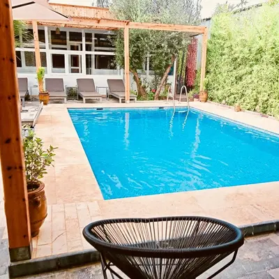 a swimming pool with a chair in front of it at Riad Eglantine in Touggana