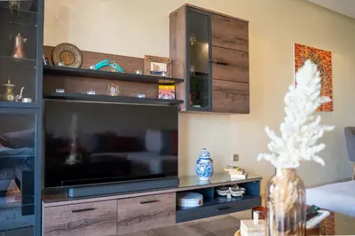 a living room with a large entertainment center with a flat screen tv at Two bedroom apartment on golf resort near airport in Marrakech