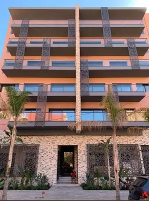 a tall building with palm trees in front of it at Charmant appartement lumineux au cœur de la ville in Marrakech