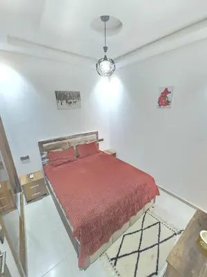 a bedroom with a bed with a red blanket at Appartement ECHRIFIA GARDENS in Marrakech