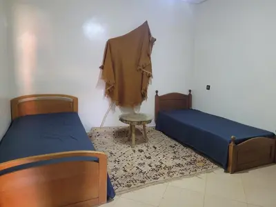 a bedroom with two beds and a table and a chair at Dar Yassan in Marrakech