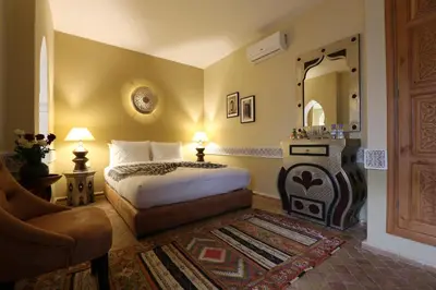a bedroom with a bed and a mirror and a chair at Riad Enchanté in Marrakech