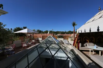 a glass roof with a patio with tables and chairs at Riad Enchanté in Marrakech
