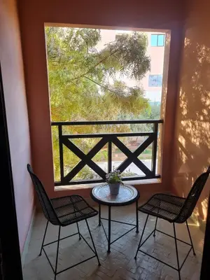 a patio with a table and two chairs and a window at Calme et sérénité 5 piscines Palmeraie in Marrakech
