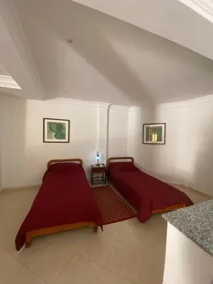 two beds in a white room with red sheets at Peaceful Retreat with pool in Marrakech
