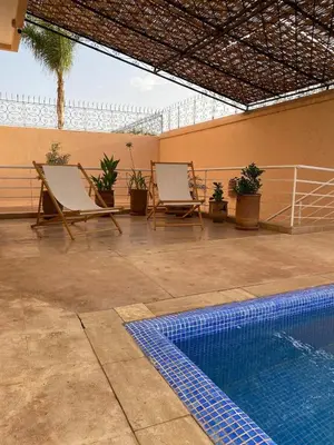 a resort with a swimming pool and two chairs and a swimming pool at Peaceful Retreat with pool in Marrakech