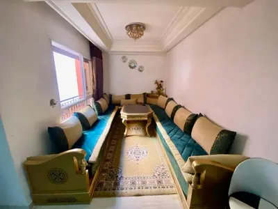 a living room with a long couch and a window at Agréable, cosy, proche du centre in Marrakech