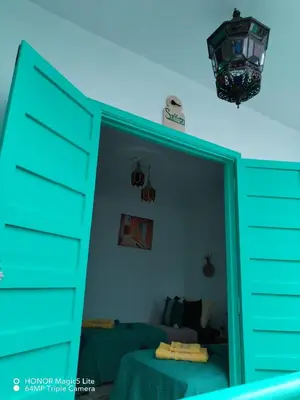 a bedroom with a blue door and a mirror at ATHIKA Hostel in Marrakech