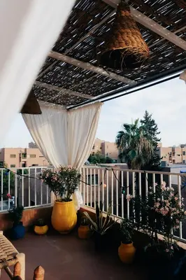 a balcony with a white curtain and potted plants at Beldi-Chic & Moroccan Sweetness in Marrakech