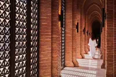 a woman in a white dress walking through a brick wall at Mandarin Oriental, Marrakech in Marrakech