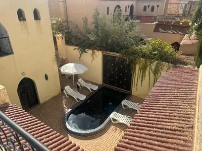 an outdoor swimming pool with two chairs and an umbrella at Cosy villa a marrakech in Marrakech