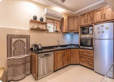 a kitchen with wooden cabinets and a stainless steel refrigerator at Oas i Medina & fantastisk terrass in Marrakech