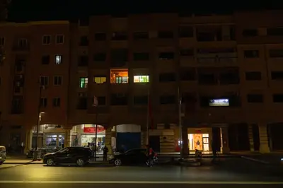 two cars parked in front of a building at night at Elegant Apartment with Moroccan Charm in Marrakech