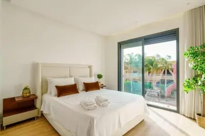 a white bedroom with a large bed and a large window at Villa moderne à 5 mins du centre-ville de Marrakech in Marrakech