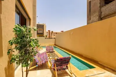 a balcony with chairs and a pool on a building at Villa moderne à 5 mins du centre-ville de Marrakech in Marrakech