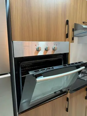 a black oven in a kitchen with wooden cabinets at La perle de Marrakech in Marrakech