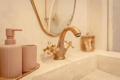 a bathroom sink with a gold faucet and a mirror at Riad KECH LeS ESSENTIELS in Marrakech