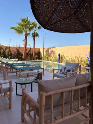 a resort with a pool and chairs and a table at Villa Marleanis 5 suites 300m2 piscine chauffée privative 11m de long résidence avec gardien in Marrakech