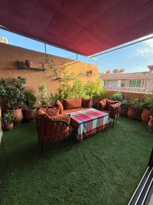 a patio with a table and chairs on the grass at Terrasse & Cinéma au cœur de Marrakech in Marrakech