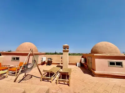 a group of chairs sitting on the roof of a building at Stylish Atlas Golf Resort Getaway - Free Breakfast, Rooftop Patio, Pool, Views in Marrakech