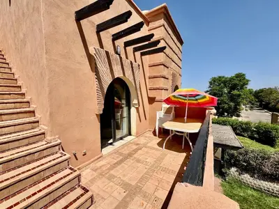 a patio with a chair and an umbrella at Stylish Atlas Golf Resort Getaway - Free Breakfast, Rooftop Patio, Pool, Views in Marrakech