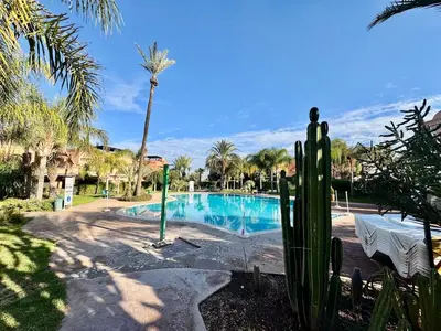 a swimming pool in a resort with a palm tree at Stylish Atlas Golf Resort Getaway - Free Breakfast, Rooftop Patio, Pool, Views in Marrakech