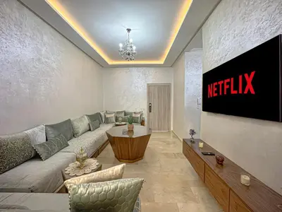 a living room with a couch and a television at charming and cozy studio with swimming pool in Marrakech