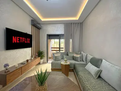 a living room with a couch and a tv at charming and cozy studio with swimming pool in Marrakech